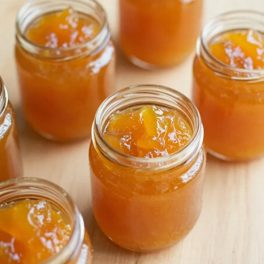 Ein Glas selbstgemachte Mirabellen-Marmelade auf einem Holztisch.