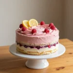 Ein cremiger Zitronen-Himbeer-Käsekuchen auf einem hellen Teller, garniert mit frischen Himbeeren und Zitronenscheiben.